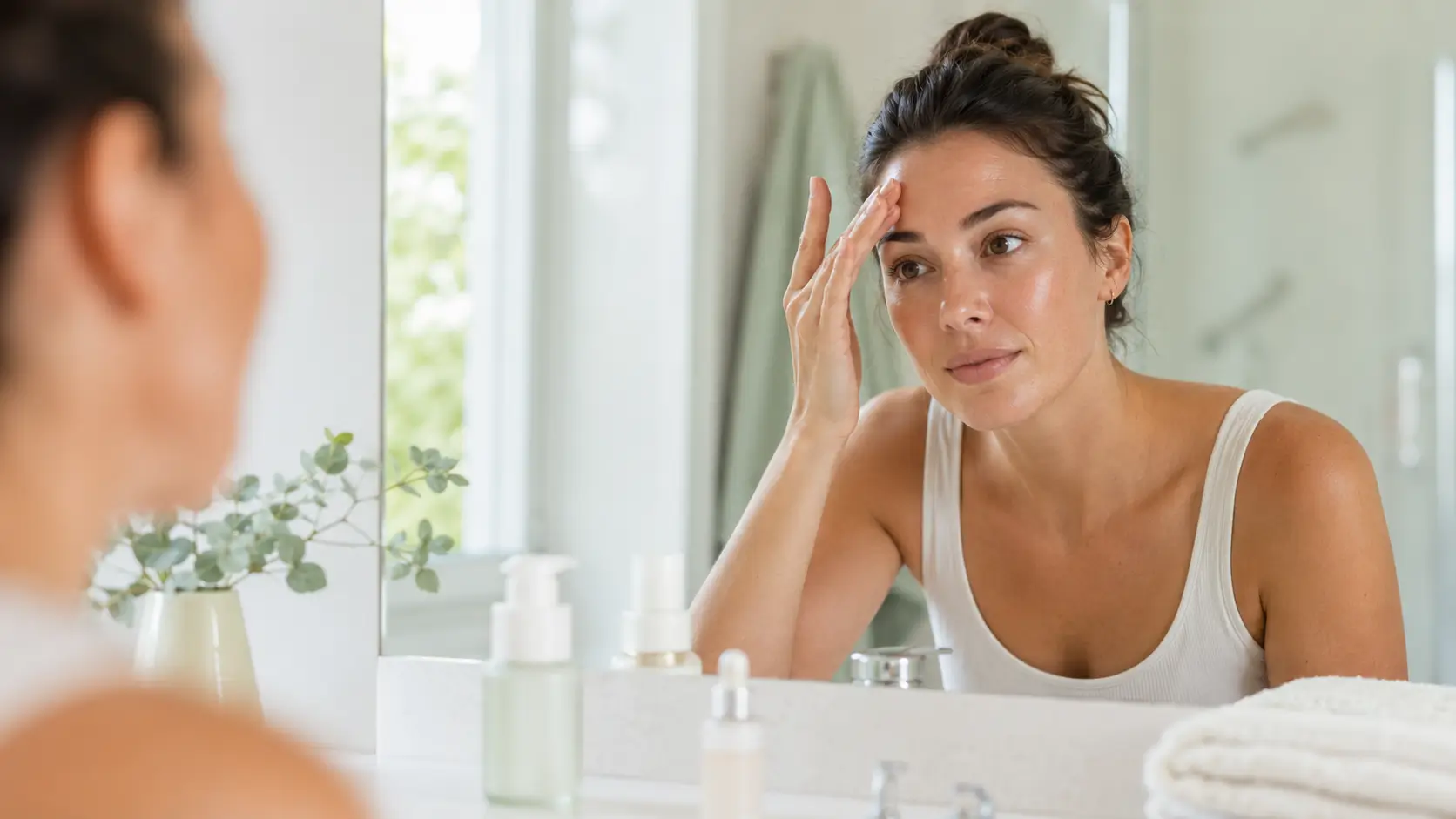 Woman checking oily skin in bathroom mirror